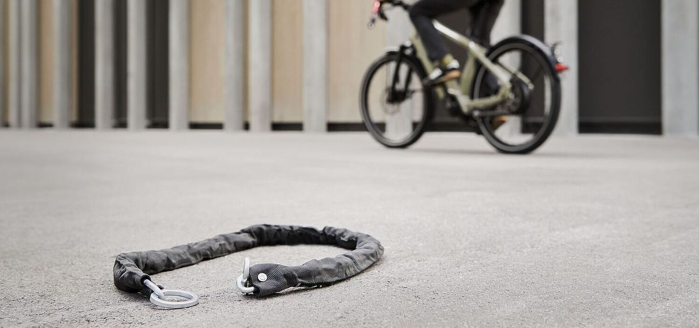 Fahrradfahrer fährt an einem Fahrradschloss vorbei, das auf dem Boden liegt.